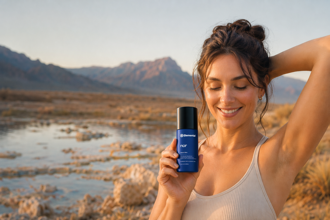 Smiling woman holding Elemental nur magnesium deodorant in a desert landscape