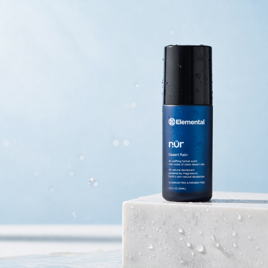 Elemental NUR Desert Rain roll-on natural deodorant on white marble with water droplets
